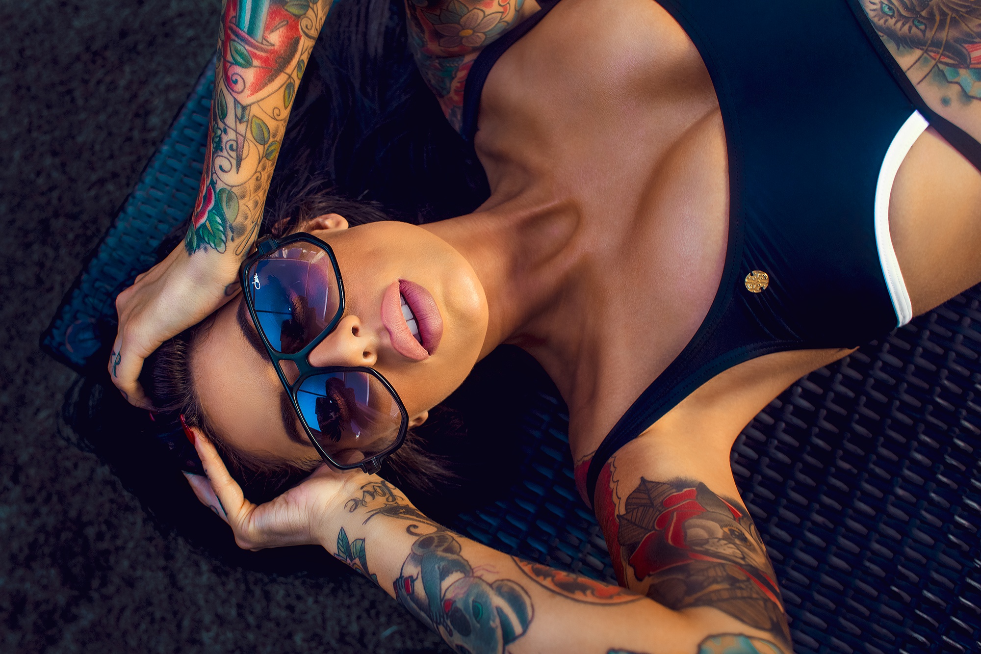 Татуированная девушка в очках с голой грудью