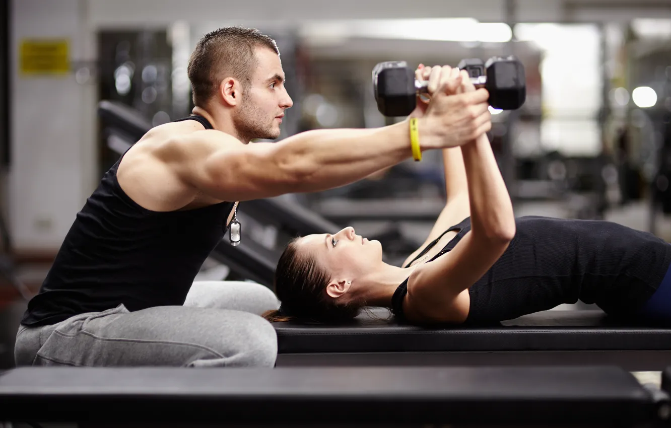 Woman Lifting Barbell While Personal Trainer Assisting Her